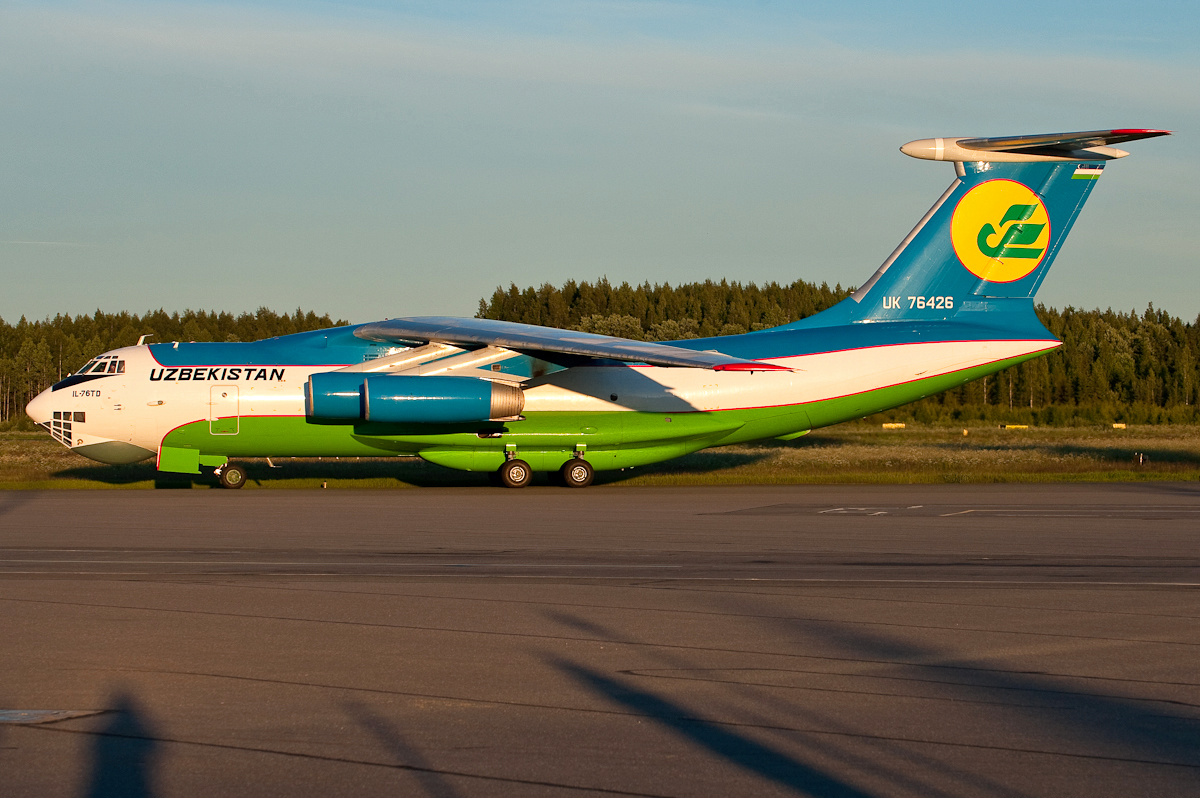 Oq-yashil-koʻk livreyadagi Uzbekistan Airways yuk Il-76TD samolyoti kechki yorugʻlikda rulyojka yoʻlagida